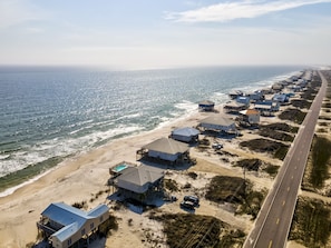 A coastal area with beachfront properties, a road, and ocean views.