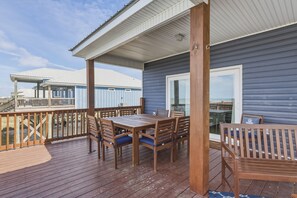 A wooden deck with a table and chairs, a bench, and a covered area with a railing. - Blue Oasis - Private Backyard Beach - Pool, Hammocks, Kayaks, Even Crab Traps So You Can Catch Dinner! 5 Bedroom Home by RedAwning (Dauphin Island)