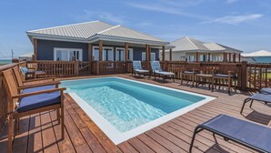 Ein Poolbereich mit Holzboden, Liegestühlen und einem Gebäude mit Metalldach.