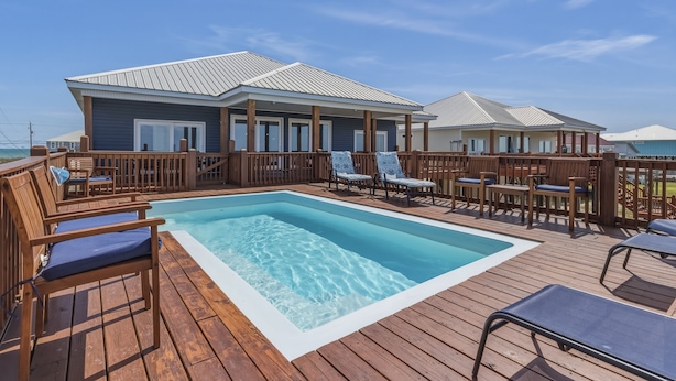 Ein Poolbereich mit Holzboden, Liegestühlen und einem Gebäude mit Metalldach.