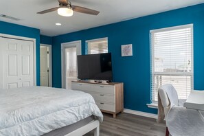 A bedroom with a bed, a dresser, a television, and a ceiling fan.