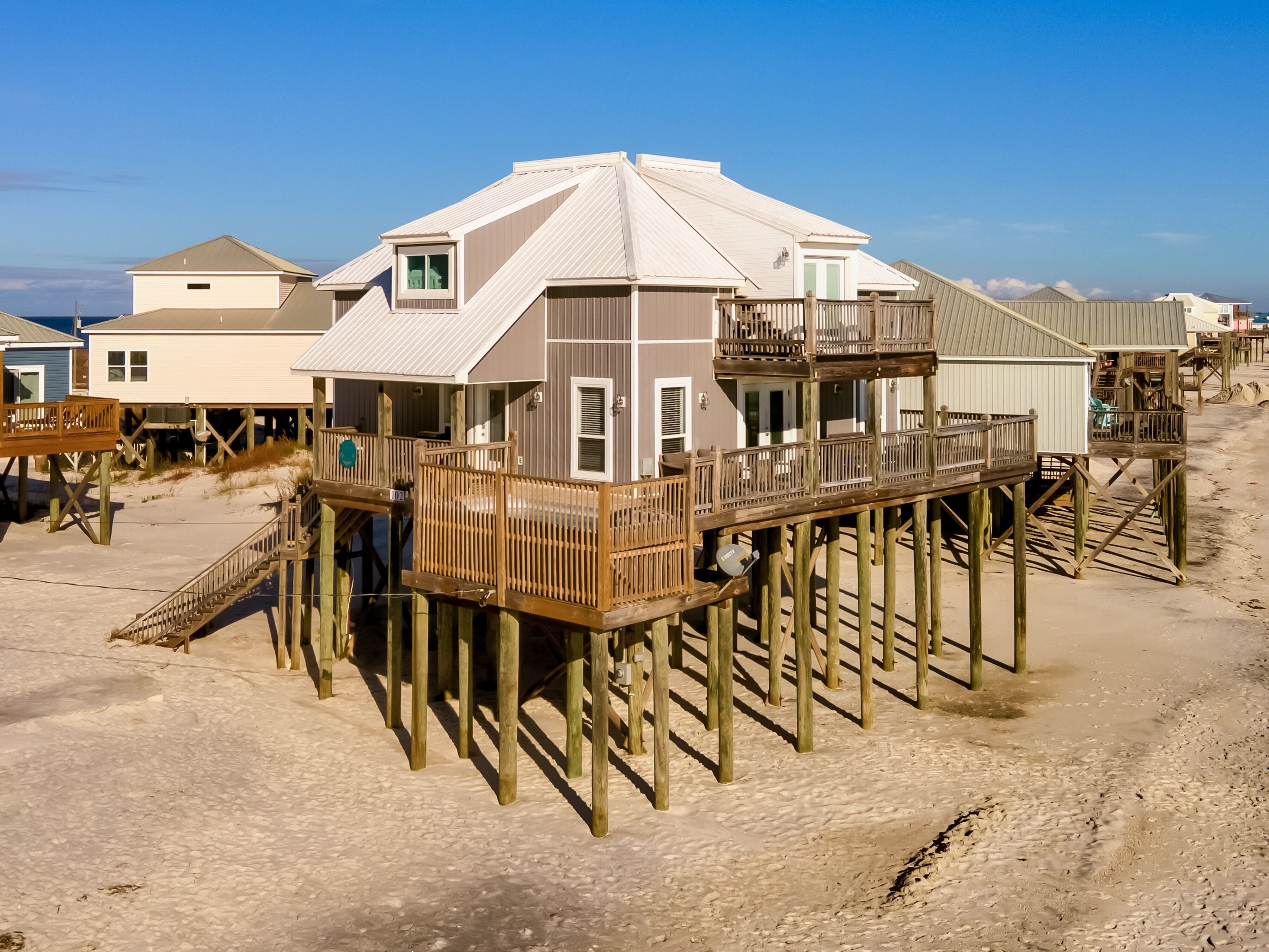 A beachfront property with multiple wooden decks and a sandy beach.