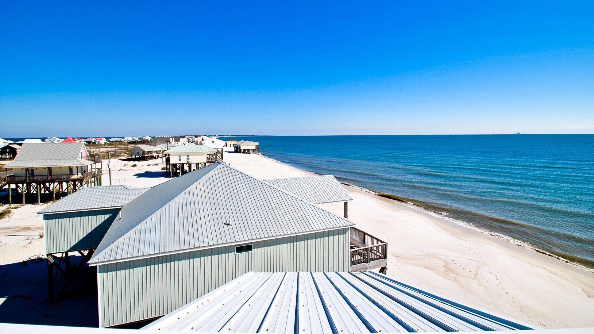 Un hotel sulla spiaggia con diversi edifici, tra cui una struttura ampia con tetto spiovente e un edificio più piccolo con tetto piatto.