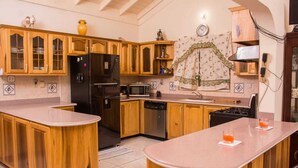 Una cocina con armarios de madera, un refrigerador negro, un microondas y un lavavajillas. Hay dos vasos pequeños en la encimera.