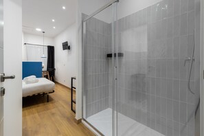 Une chambre d’hôtel moderne équipée d’une douche, d’un lit et d’une télévision.