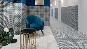Un couloir moderne avec un mur d’accent bleu, un revêtement de sol carrelé à motifs et un fauteuil turquoise.