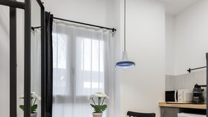 Une cuisine compacte avec un coin repas, comprenant une table ronde avec des chaises, un four à micro-ondes et une machine à café.