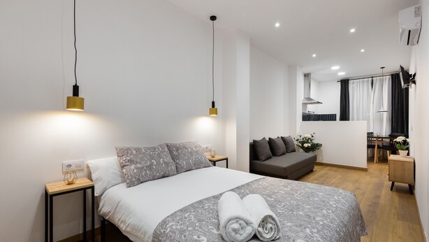 Une chambre moderne avec un grand lit, des tables de chevet, un canapé et un petit coin repas.