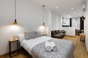 A modern bedroom with a large bed, bedside tables, a sofa, and a small dining area. - Hotelito Boutique Valencia Estación (Valencia)