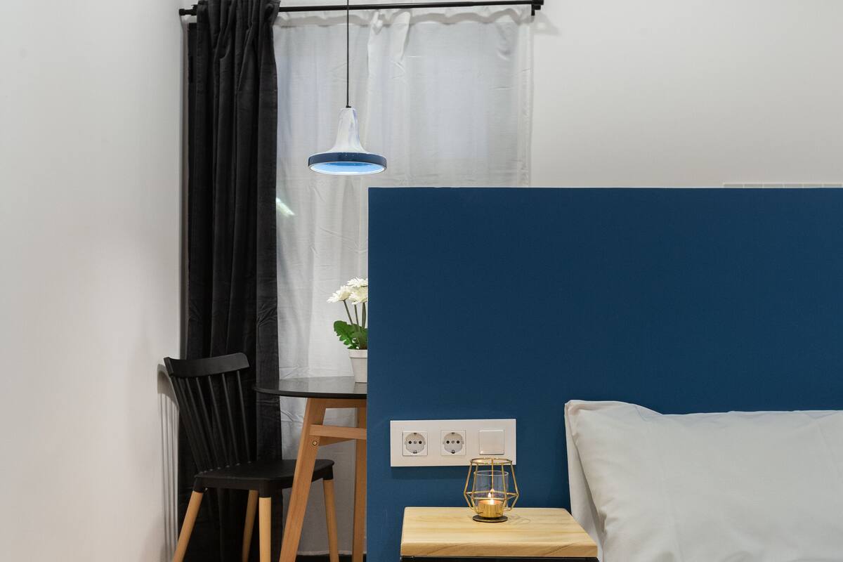A small, neatly arranged room with a bed, a desk, and a chair.