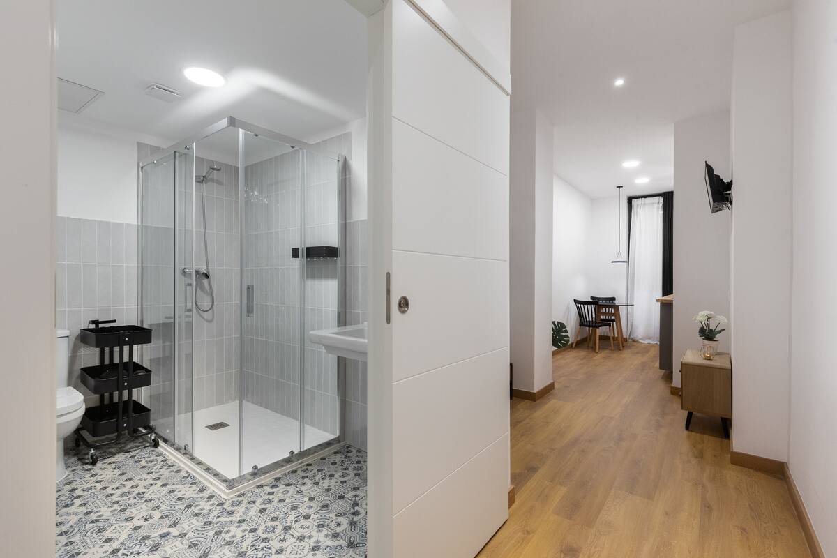 A modern bathroom with a glass shower enclosure, a toilet, and a sink.