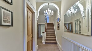 A hallway with a carpeted staircase, wooden doors, and a large mirror on the wall.