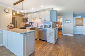 A modern kitchen with white cabinetry, a central island, stainless steel appliances, and pendant lighting.
