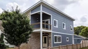 A two-story residential building with a balcony, a stone facade, and a wooden fence. - Minutes from Anything Downtown Indy! (Indianapolis)
