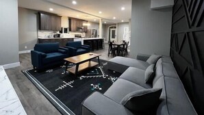 A modern living room with a sofa, a coffee table, and a dining area with chairs. - Minutes from Anything Downtown Indy! (Indianapolis)