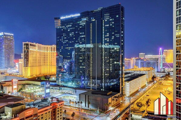 A high-rise hotel with a modern glass facade, located in a bustling urban area with other buildings and a busy street.
