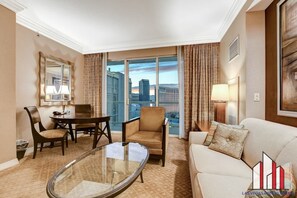A hotel room with a dining table, two chairs, a sofa, a glass coffee table, and a large window offering a city view. - MGM Signature-22-707 F1 Track & Strip View Balcony (Las Vegas)