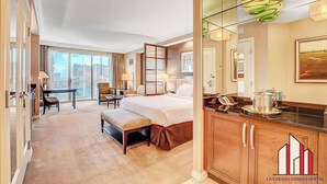 A hotel room with a large bed, a desk, a chair, a dining table, and a view of the city. - MGM Signature-  Studio F1 Track Strip View Balcony (Las Vegas)