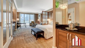 A hotel room with a large bed, a desk, a chair, a small table, and a view of the city. - Luxury Studio | Jacuzzi, Balcony & Full Bath (Las Vegas)