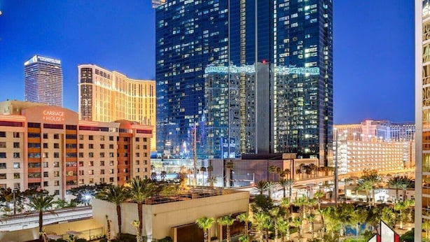 A hotel with a modern design, featuring a prominent glass facade and a rooftop area with outdoor seating. - Luxury Studio | Jacuzzi, Balcony & Full Bath (Las Vegas)