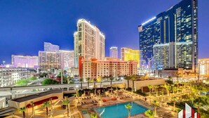 A hotel with a pool area, multiple high-rise buildings, and a well-lit urban skyline. - Luxury Studio | Jacuzzi, Balcony & Full Bath (Las Vegas)