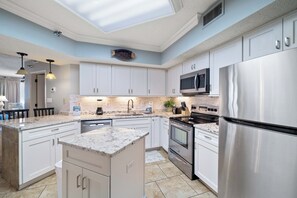 Una cocina moderna con armarios blancos, electrodomésticos de acero inoxidable y un tragaluz.