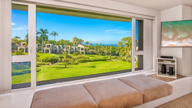 A room with a large window offering a view of a golf course and buildings. - Elegant Wailea Retreat Near Keawakapu Beach & Resort Amenities (Kihei)
