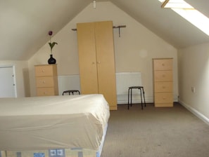 Cozy attic retreat with a bed, wardrobe, and radiator, offering a peaceful space to unwind.