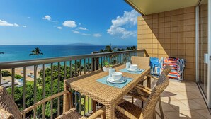 Un balcone con vista sull'oceano, mobili in vimini e una spiaggia sullo sfondo.