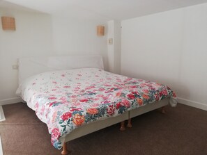 A single bed with a floral bedspread, a plain white wall, and a brown carpet. - Beautiful waterfront residence, private pool, sun terrace (Le Croisic)