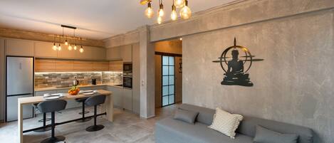 Una cucina moderna con zona pranzo, un divano grigio e un'opera d'arte appesa al muro.