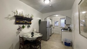 A compact kitchen with a dining area, white walls, and a tiled floor. - 6649 1E | Garden Style Studio Near Forest Park (St. Louis)