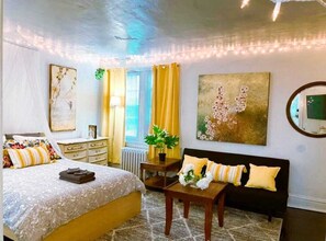 Un dormitorio con cama, mesita de noche y un cuadro grande en la pared.