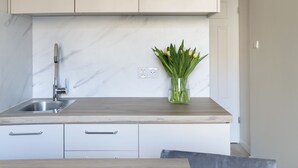 A modern kitchen with light-colored cabinets, a marble backsplash, and a wooden countertop. - Elite Apartments Garncarska (Gdansk)
