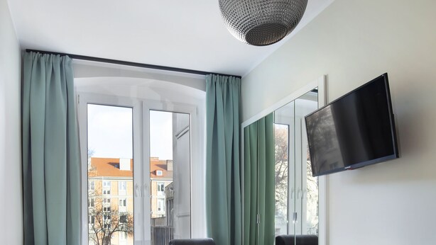 Un soggiorno moderno con un divano grigio, un tavolino rotondo e una TV fissata alla parete.