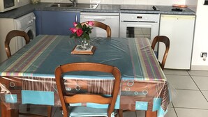Cuina amb armaris blaus, taula de menjador amb mantell de taula colorit i un ram de flors.