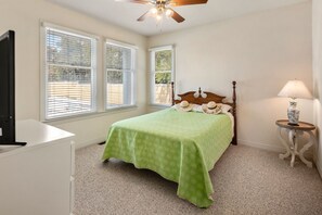 A bedroom with a bed, a ceiling fan, a nightstand, a lamp, and two windows with blinds. - Boromacha: Private Pool, Hot Tub, Club Access (Corolla)