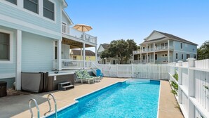 Une piscine résidentielle dotée d’un patio couvert, de chaises longues et d’un jacuzzi.