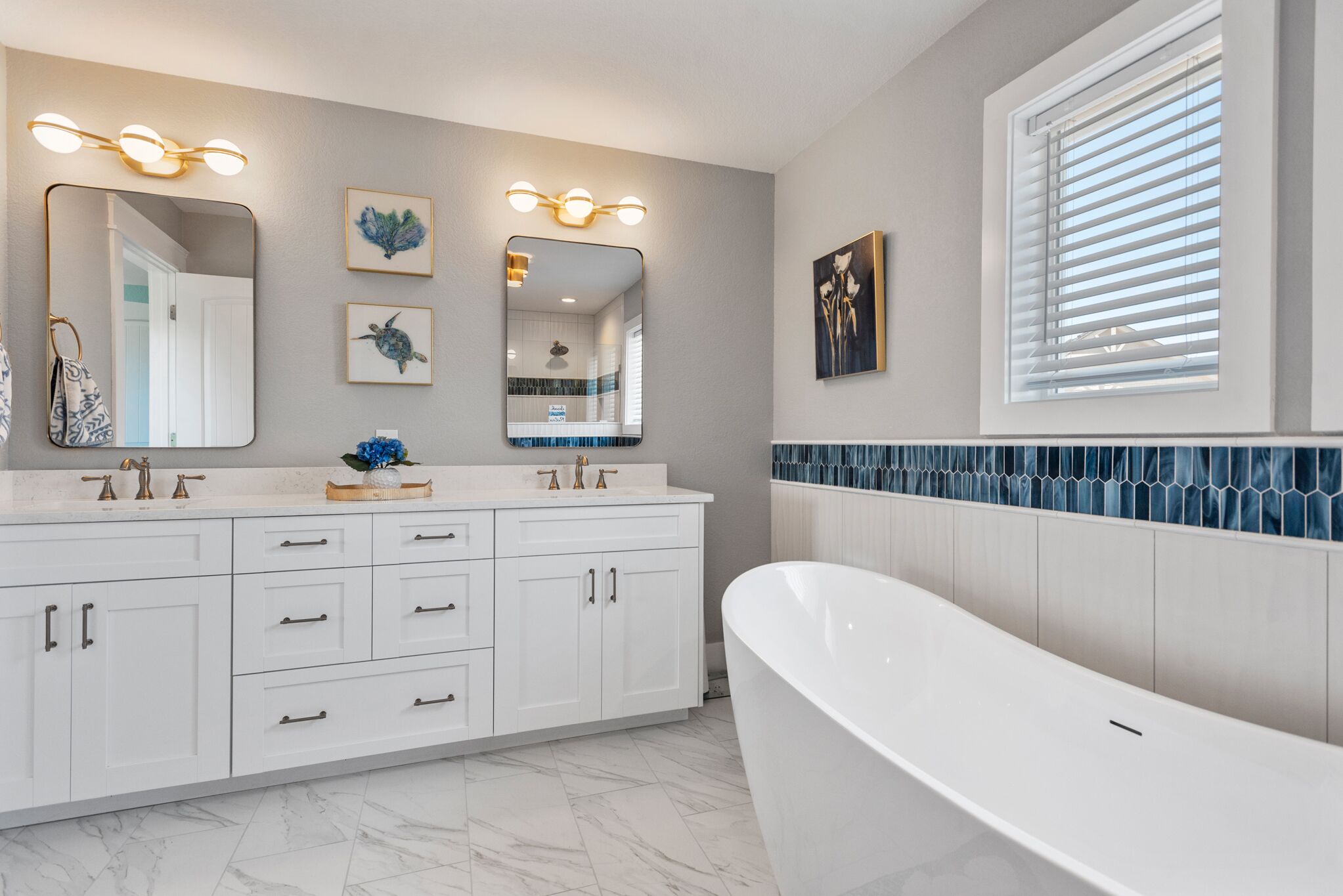 A modern bathroom with a freestanding bathtub, a vanity with a mirror, and a window with blinds.