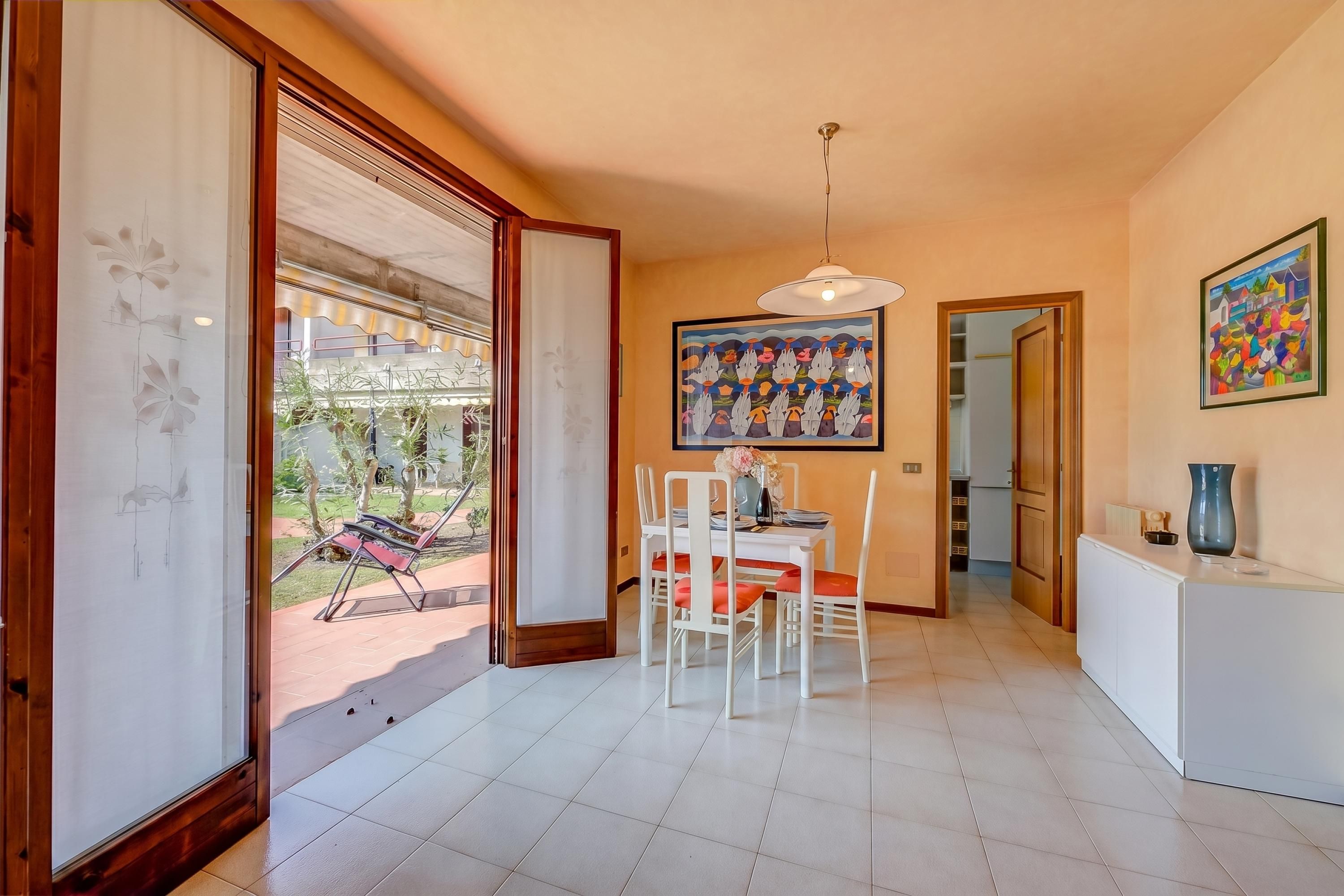 Zona pranzo con tavolo e sedie, una lampada a soffitto e un quadro appeso al muro.