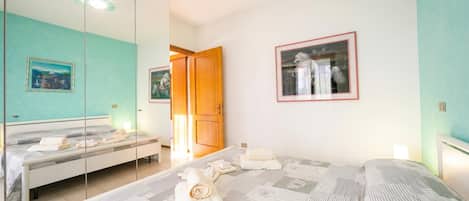A bedroom with a bed, a mirror, a wardrobe, and a painting on the wall.