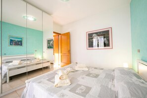Une chambre à coucher avec un lit, un miroir, une armoire et un tableau accroché au mur.