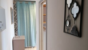 Un pasillo con piso de madera, una puerta que da a una habitación, un armario pequeño y un adorno en la pared.