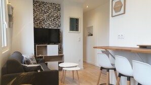 Una sala de estar moderna con un sofá, un televisor, una mesita y dos sillones.