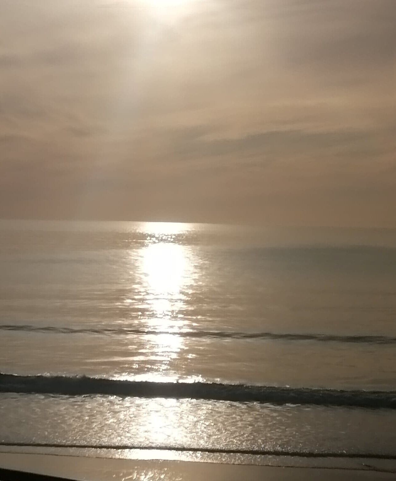 En strand där solen speglas i vattnet.