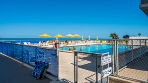 A pool area with yellow umbrellas, a sign indicating no smoking and no glass, and a sign pointing to the office.