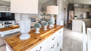 A modern kitchen with white cabinetry, a wooden countertop, and a central island with bar stools.