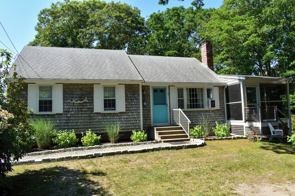 A single-story house with a front porch, a blue door, and a chimney.
