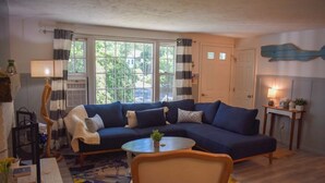 Ein Wohnzimmer mit einem blauen Sofa, einem runden Couchtisch, einem Sessel und einer Lampe.
