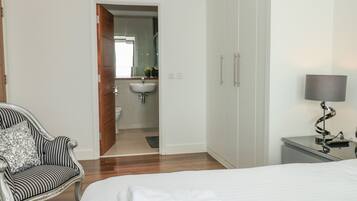 A bedroom with a bed, a bedside table with a lamp, a chair, and a wardrobe.